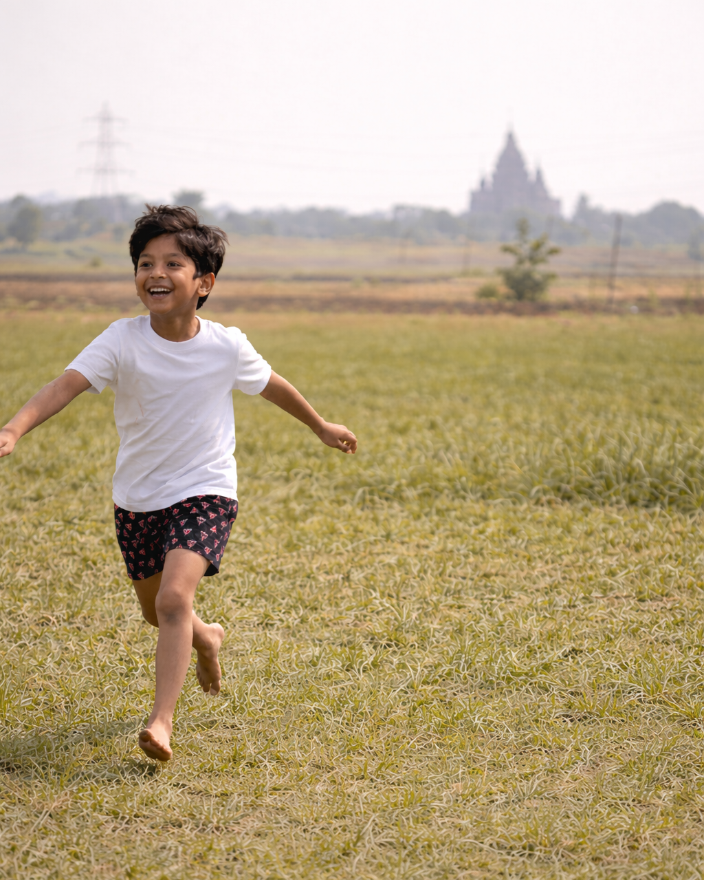Child running on a grassy field with a blurred landscape in the background