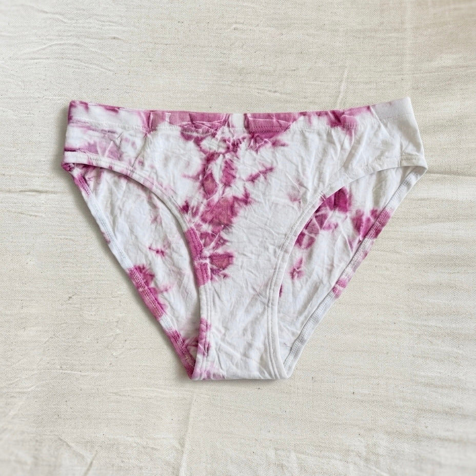 Pink and white tie-dye underwear on a light beige surface