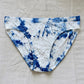 Blue and white tie-dye bikini bottom on a light gray surface