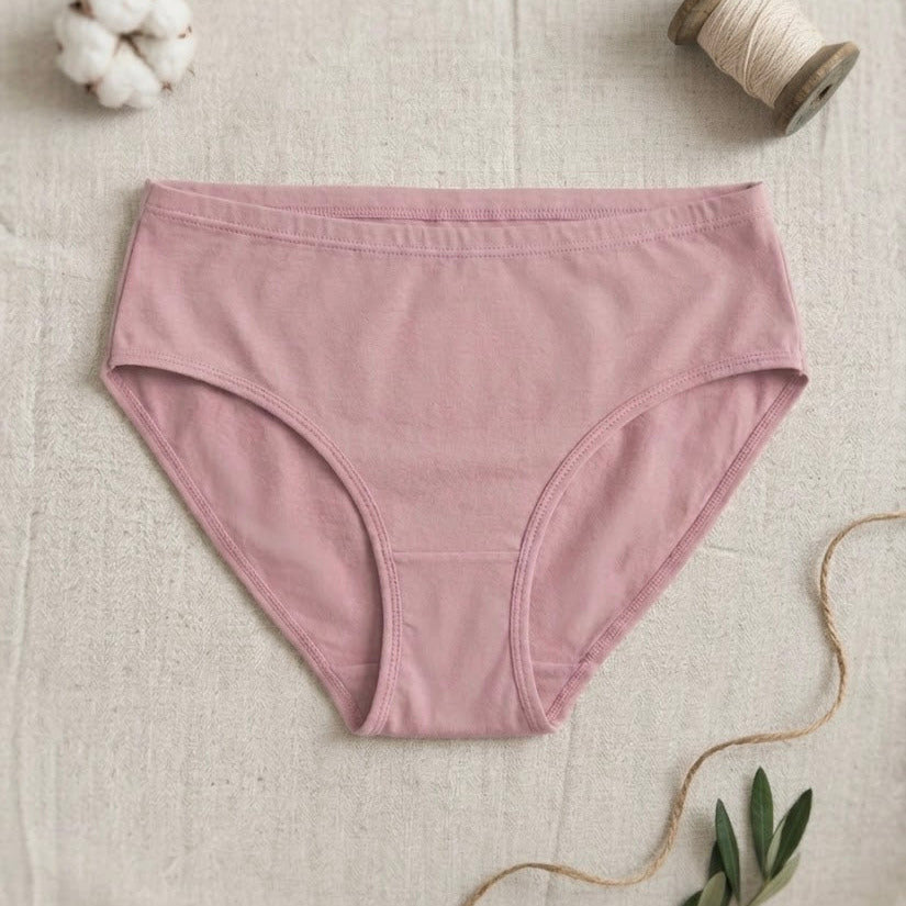 Pink underwear on a textured beige surface with cotton bolls and twine.