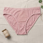 Pink underwear on a textured surface with a spool of thread and green leaves.
